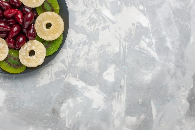 Draufsicht getrocknete Früchte Ananasringe und Kiwischeiben auf hellweißem Hintergrundfrucht trockener süßer Zucker sauer