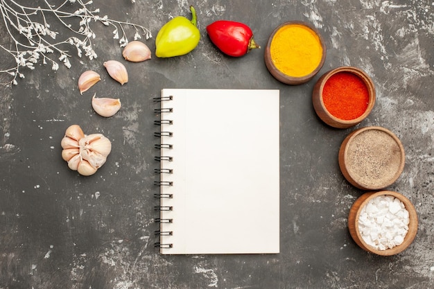 Draufsicht Gewürze auf dem Tisch Knoblauch bunte Gewürze Kugelpfeffer auf dem dunklen Tisch