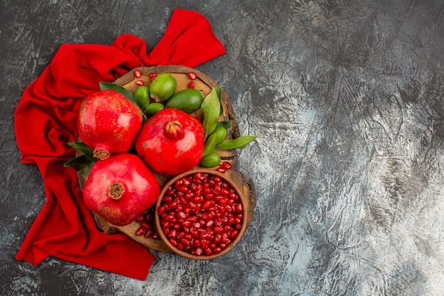 Draufsicht Granatäpfel drei Granatapfel Granatapfelkerne auf dem Brett auf der roten Tischdecke