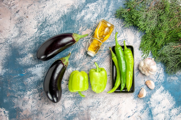 Kostenloses Foto draufsicht grüne peperoni auf schwarzem teller knoblauchöl auberginen paprika auf blau-weißem hintergrund