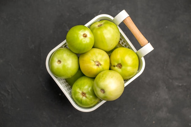 Draufsicht grüne Tomaten im Korb auf dunklem Hintergrund