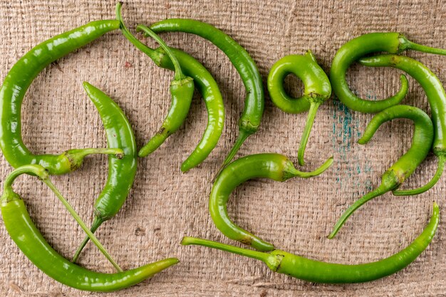 Draufsicht grüner Chili Pfeffer auf beigem Leinen horizontal