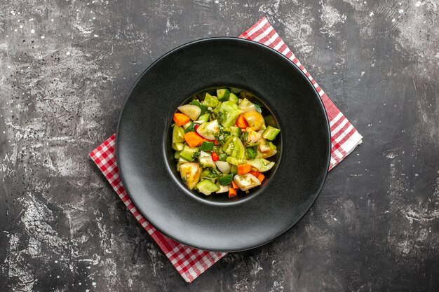 Draufsicht grüner Tomatensalat auf ovalem Teller auf Serviette auf dunklem Hintergrund