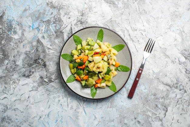 Draufsicht grüner Tomatensalat auf ovaler Platte eine Gabel auf grauem Hintergrund