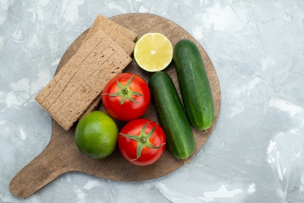 Draufsicht gurken und tomaten mit limetten und chips auf grau