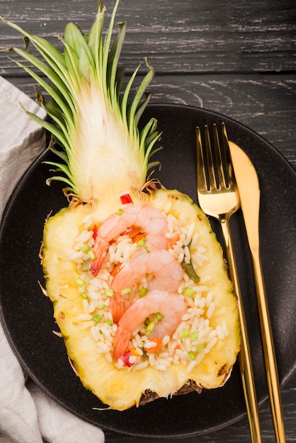 Draufsicht Hälfte der Ananas mit Garnelen und goldenem Besteck