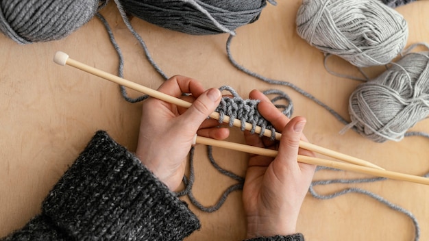 Kostenloses Foto draufsicht hände, die stricknadeln halten