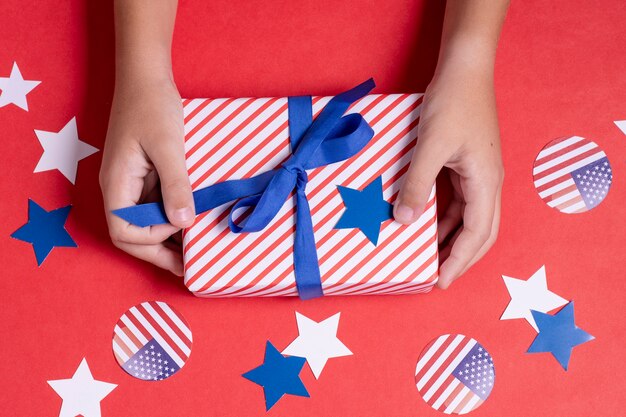 Draufsicht Hände, die USA Flagge verpacktes Geschenk mit Dekoration halten