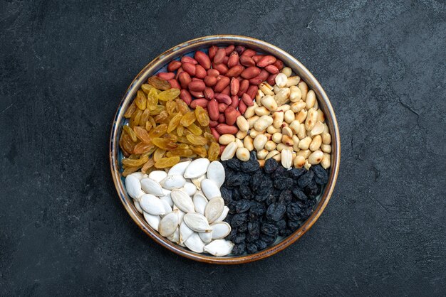 Draufsicht Haselnüsse und Rosinen und andere Nüsse auf dunkelgrauem Oberflächennuss-Snack-Trockenfruchtfoto