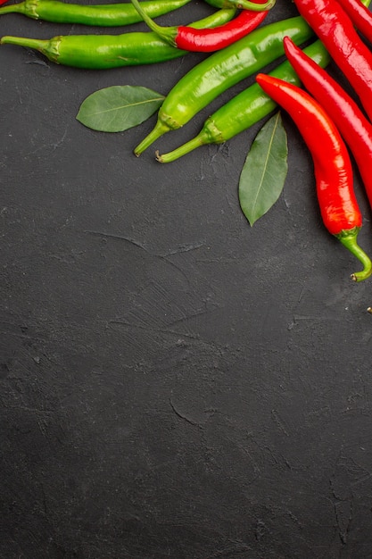 Draufsicht heiße rote und grüne Paprika Lorbeerblätter an der Oberseite des schwarzen Tisches mit freiem Raum