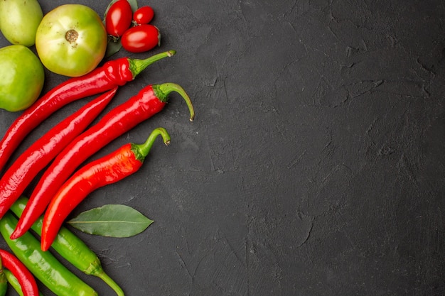 Draufsicht heiße rote und grüne Paprika und Tomaten Lorbeerblätter auf der linken Seite des schwarzen Bodens mit freiem Raum