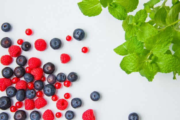 Draufsicht Himbeeren mit Blaubeeren, roten Johannisbeeren, Minzblättern auf weißem Hintergrund. horizontal