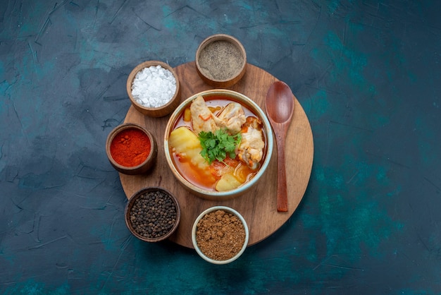 Draufsicht Hühnersuppe zusammen mit Gewürzen auf der dunkelblauen Schreibtischsuppe Fleischessen Abendessen