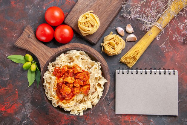 Draufsicht Huhn mit Teig Nudelgericht mit Tomaten auf dunkler Oberfläche Nudelteig Mahlzeit