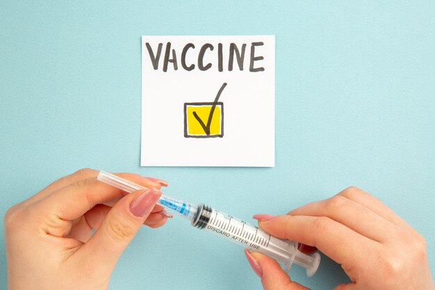 Draufsicht Impfstoffnotiz geschrieben von Frau auf blauem Hintergrund Impfstofflabor Pandemie Krankenhaus Wissenschaft Covid-Virus Gesundheit