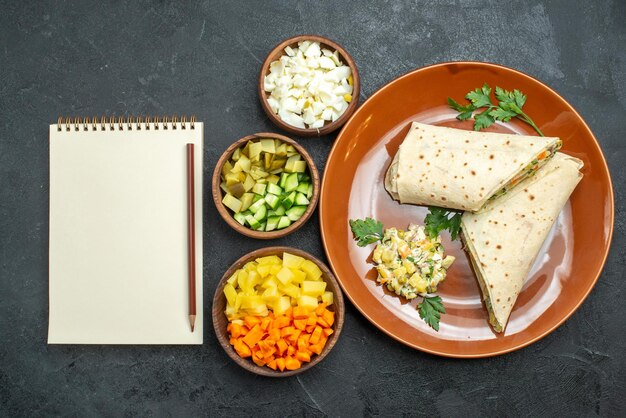 Draufsicht in Scheiben geschnittenes shaurma leckeres Fleisch- und Salatsandwich auf grauem Schreibtisch Burger-Sandwich-Salat-Brot-Pita-Fleisch