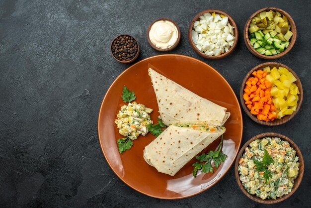 Draufsicht in Scheiben geschnittenes shaurma leckeres Fleischsandwich mit Salatzutaten auf der dunklen Oberfläche Burger-Sandwich-Brot-Pita-Fleisch