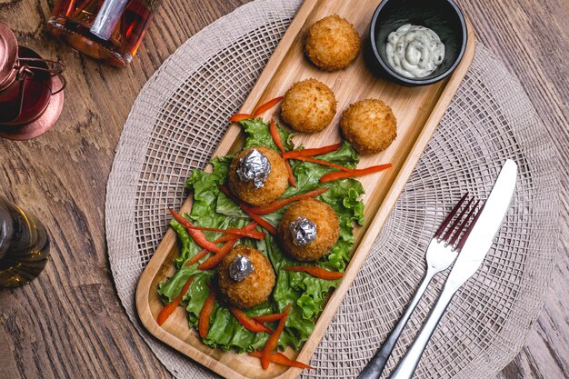 Draufsicht-Käsebällchen auf Salatblättern mit Soße