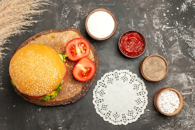 Kostenloses Foto draufsicht käsiger fleischburger mit gewürzen auf den dunklen schreibtischbrötchen-sandwich-fleisch-pommes