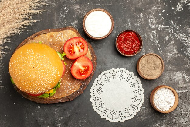 Draufsicht käsiger Fleischburger mit Gewürzen auf den dunklen Schreibtischbrötchen-Sandwich-Fleisch-Pommes