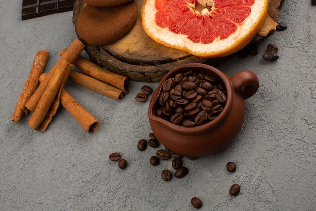 Draufsicht Kaffee braune Samen zusammen mit Zimt und Grapefruit auf dem grauen Boden