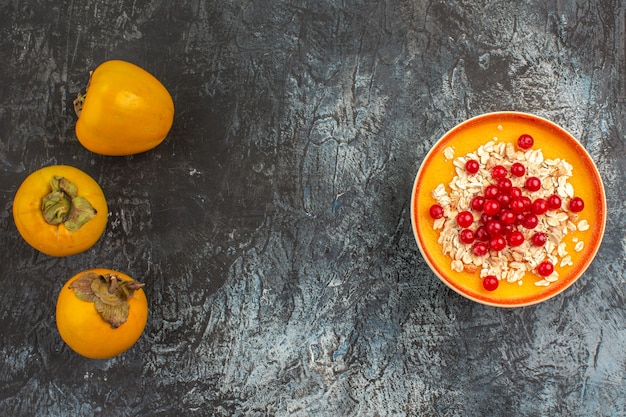 Draufsicht Kaki die appetitlichen Kakis neben der Schüssel Beeren auf dem Tisch