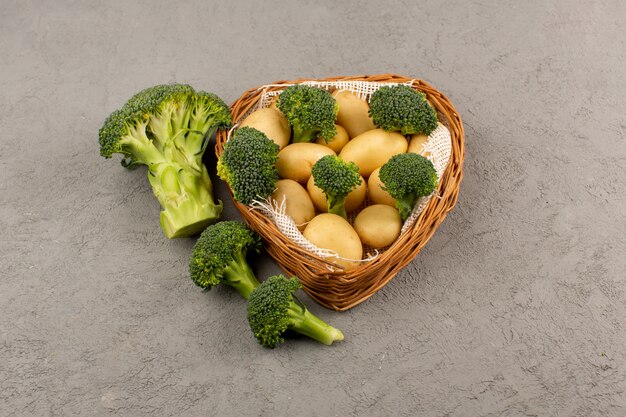 Draufsicht Kartoffeln und Brokkoli frisch reif im Korb auf dem grauen Boden