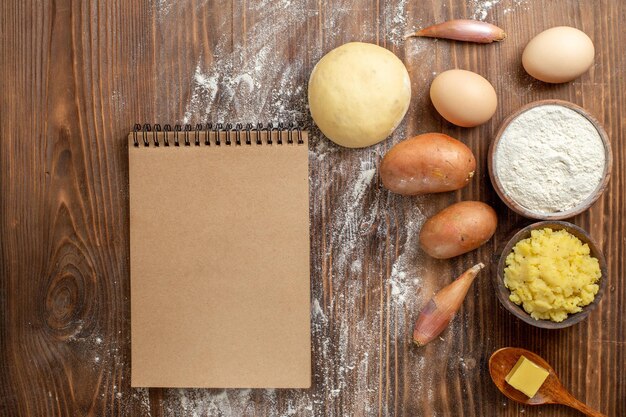 Draufsicht Kartoffelpüree mit Mehl und Kartoffeln auf braunem Holzschreibtisch würziger Pfeffer reife Kartoffelnahrung