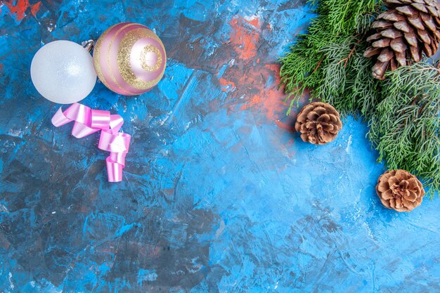 Draufsicht Kiefer Zweige Tannenzapfen Weihnachtsbaum Kugeln auf blau-roter Oberfläche