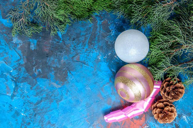 Draufsicht Kiefer Zweige Tannenzapfen Weihnachtsbaum Kugeln Band auf blau-roter Oberfläche