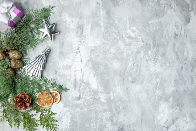 Draufsicht Kiefer Zweige Zitronenscheiben Tannenzapfen Weihnachtsbaum Spielzeug auf grauem Hintergrund Kopie Raum