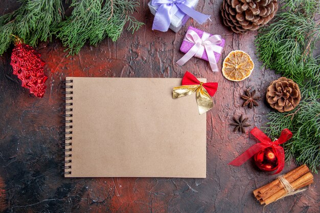 Draufsicht Kieferzweige mit Zapfen Anis Zimt Weihnachten Details ein Notizbuch auf dunkelroter Oberfläche
