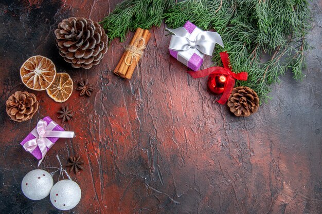 Draufsicht Kieferzweige mit Zapfen Weihnachtsbaum Spielzeug Zimt getrocknete Zitronenscheiben Sternanis auf dunkelrotem Hintergrund Freiraum