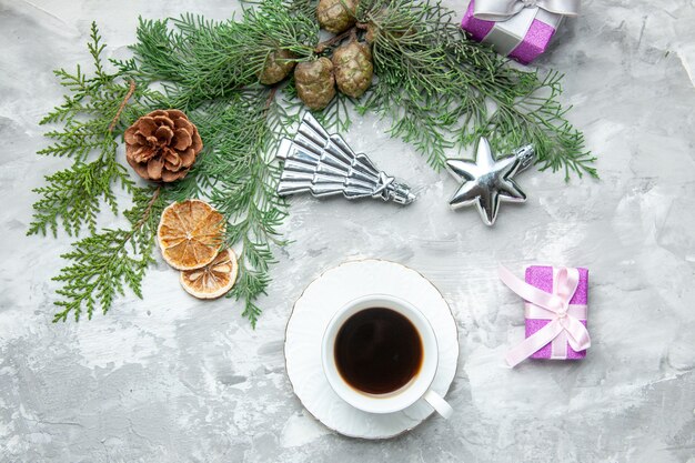 Draufsicht Kieferzweige Tasse Tee getrocknete Zitronenscheiben Tannenzapfen kleine Geschenke auf grauer Oberfläche