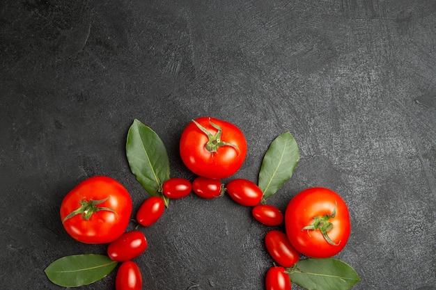 Draufsicht Kirschbaum und rote Tomaten Lorbeerblätter auf dem Boden des dunklen Bodens mit Kopierraum