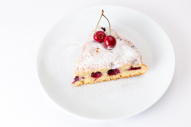 Draufsicht Kirschkuchenscheibe innerhalb weißer Platte mit Zuckerpulver auf dem weißen Hintergrundkuchen süßer Zuckerteig backen