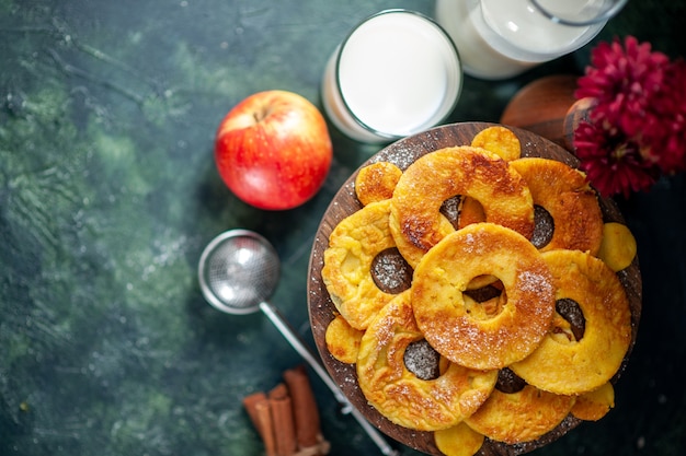 Kostenloses Foto draufsicht kleine köstliche kuchen in ananasringform mit milch auf dunklem hintergrund