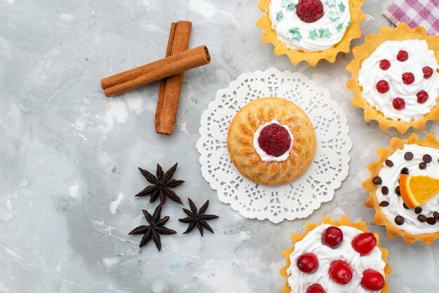 Draufsicht kleine köstliche Kuchen mit Zimt auf dem grauen Schreibtisch süß