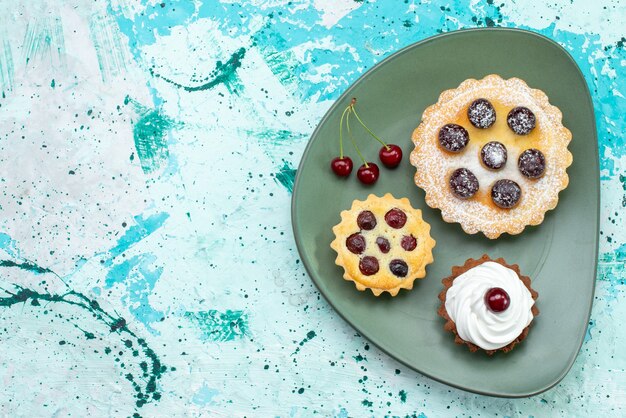 Draufsicht kleine Kuchen mit Zuckerpulverfruchtcreme innerhalb grüner Platte auf hellem Hintergrundkuchencremefrucht süßer Tee