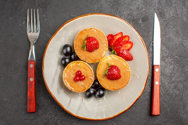 Draufsicht kleine leckere Pfannkuchen mit Früchten auf der dunkelgrauen Oberfläche Tortenkuchenfrucht