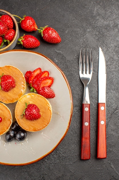 Draufsicht kleine leckere Pfannkuchen mit Früchten auf dunkelgrauem Bodenkuchenkuchenfrucht