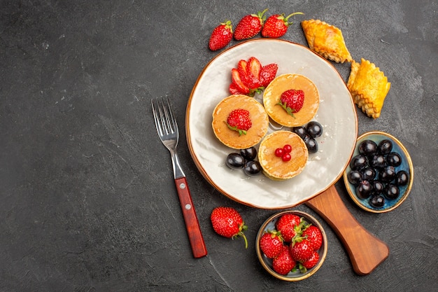 Draufsicht kleine leckere Pfannkuchen mit Früchten auf dunklem Oberflächenkuchenfruchtkuchen