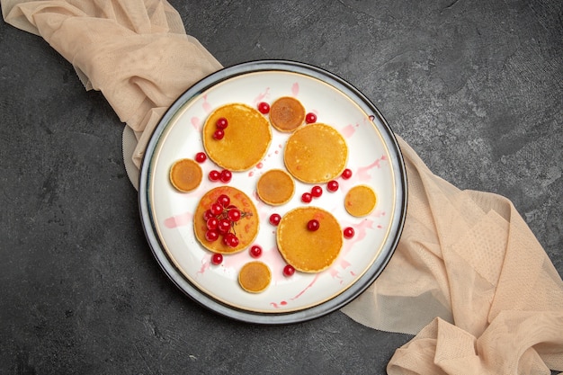 Draufsicht kleine Pfannkuchen mit roten Beeren auf dunkelgrau