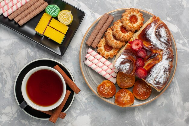 Draufsicht kleine Pfeifenkekse mit Marmeladentasse Tee und kleinen Kuchen auf weißem Hintergrundplätzchenkekszuckerkuchen