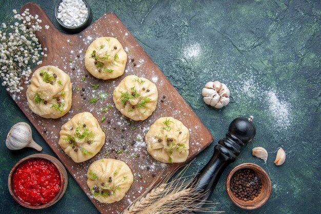 Draufsicht kleine rohe Knödel mit Fleisch und Tomatensauce auf der dunkelblauen Oberfläche Fleischteigküche Gericht Kuchen Abendessen Abendessen Kochen