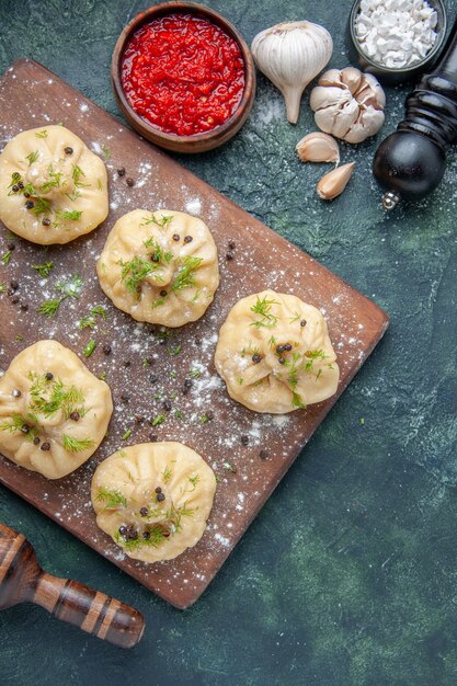 Kostenloses Foto draufsicht kleine rohe knödel mit fleisch und tomatensauce auf dunkelblauer oberfläche fleisch teiggericht kuchen abendessen abendessen kochen