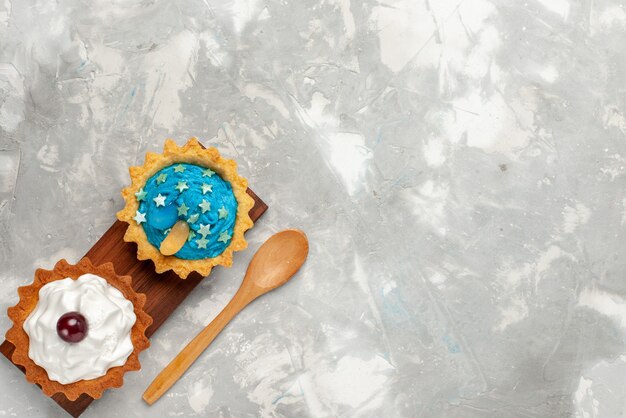 Draufsicht kleine Sahnekuchen auf leichtem Schreibtischkuchencreme backen süßen Tee