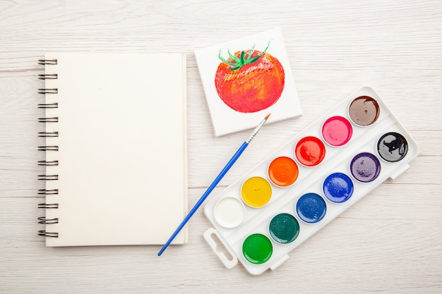 Draufsicht kleine Tomatenzeichnung mit bunten Farben auf weißem Tisch