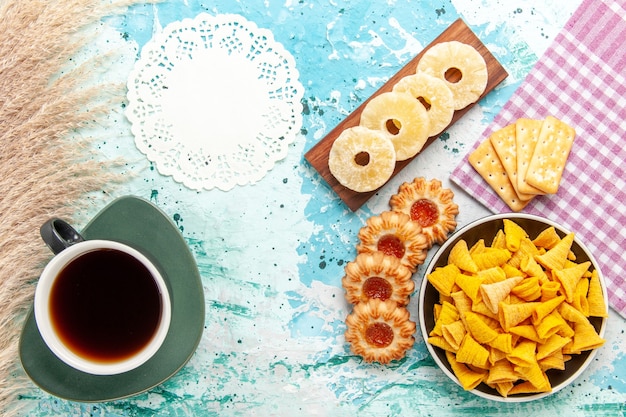 Draufsicht kleine würzige chips mit crackern getrockneten ananasringen und keksen auf hellblauen schreibtischchips snackfarbe knackige kalorien