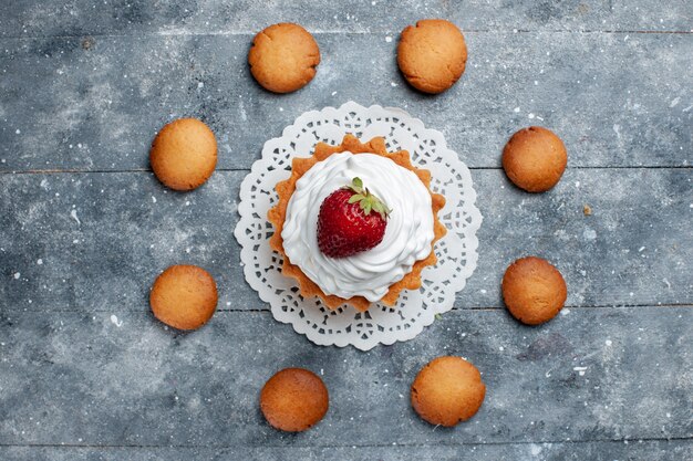 Draufsicht kleiner cremiger Kuchen gebacken köstlich isoliert mit Erdbeere zusammen mit Keksen auf dem grauen hellen Schreibtischkuchenkeks süße Farbe Sahnezucker